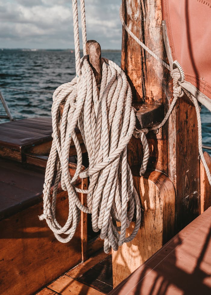 A detailed view of a wooden boat deck with coiled rope during the day, emphasizing nautical elements.