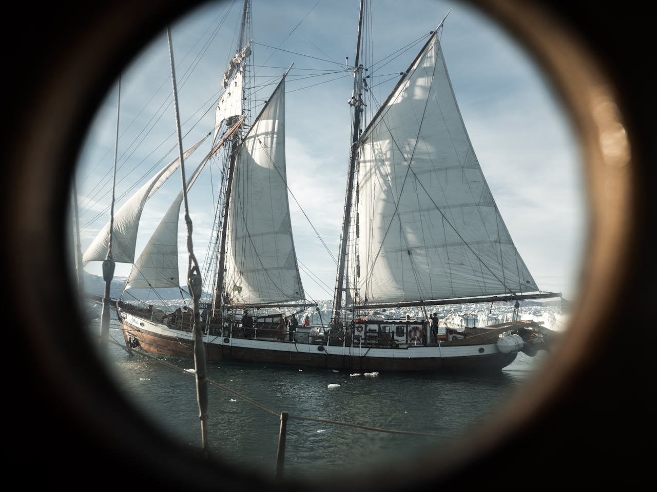 A vintage sailboat viewed through a porthole, capturing the essence of nautical adventure.