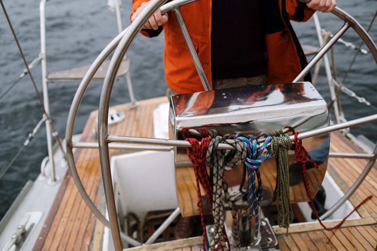 Close-up of a sailor holding the helm of a sailboat, navigating the open sea.